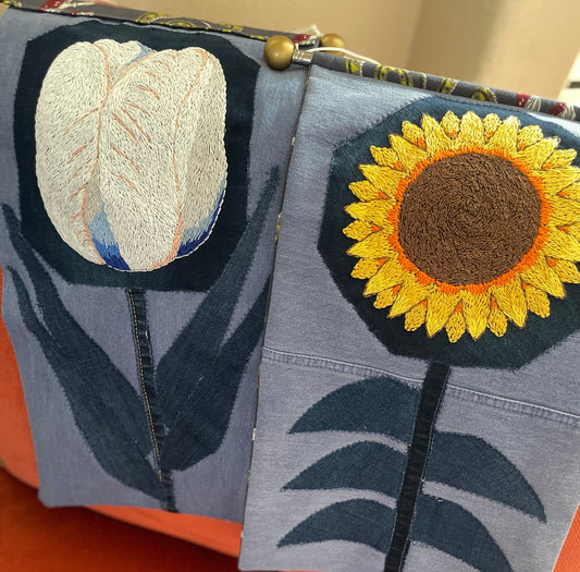 embroidered white tulip and yellow and orange sunflower tapestries on denim