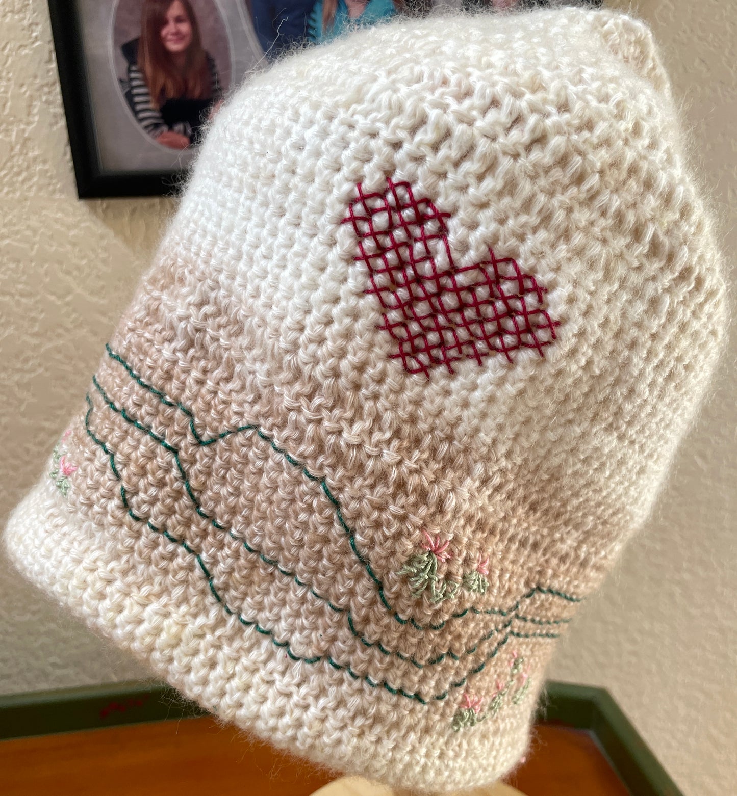 Embroidery on cap inspired by a hike.  Includes a red heart, light green and pink cactus-inspired designs.  Paths circle the cap, inspired by the hiking map.